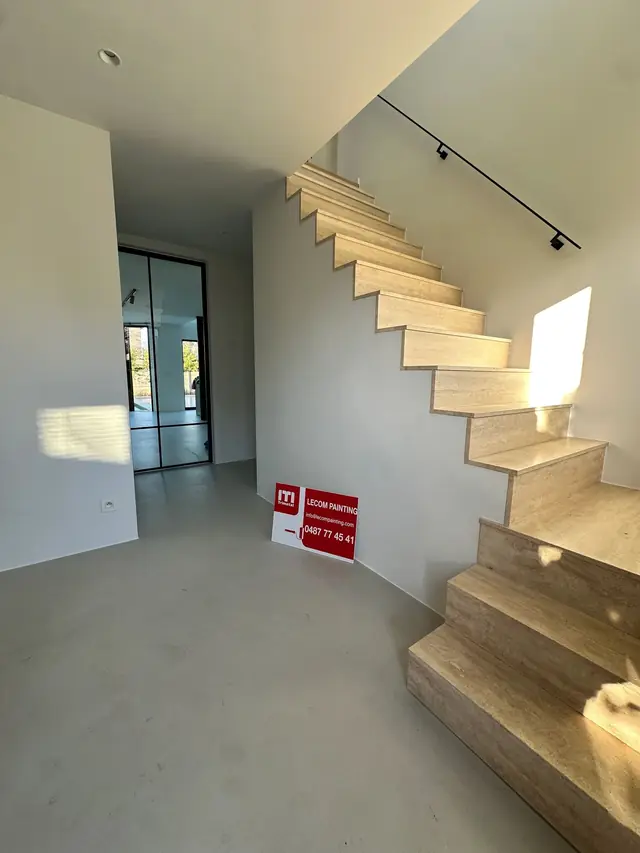 Wit geschilderde inkom met zwevende trap in een nieuwbouwwoning