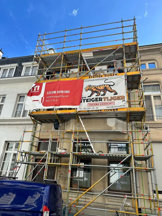 Gevelschilderwerken Antwerpen: rijwoning in de stelling tijdens het schilderen van de gevel
