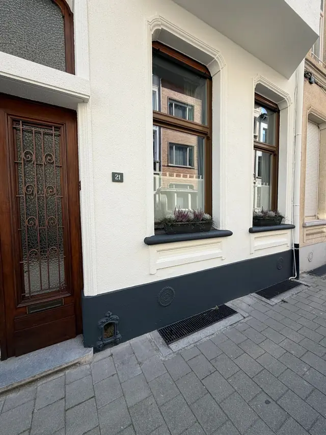 Schilderwerken Antwerpen: wit geschilderde gevel met antraciet plint en houten deur