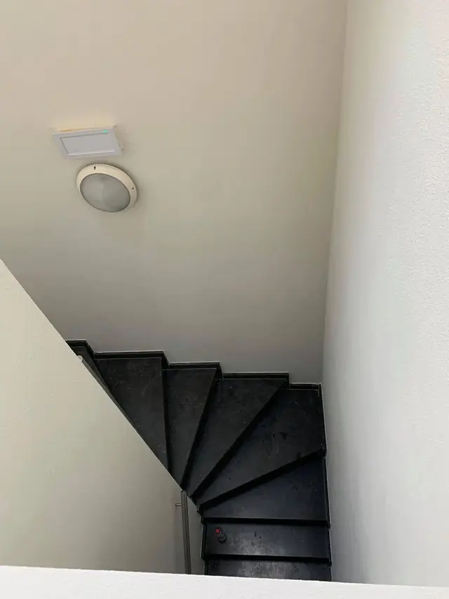 Trappenhal schilderen Antwerpen: zicht van boven op een wit geschilderde trappenhal met zwarte trap